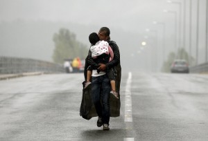 Een Syrische vader loopt met zijn dochter op de armen naar Eidomeni, de grens tussen Griekenland en FYROM.